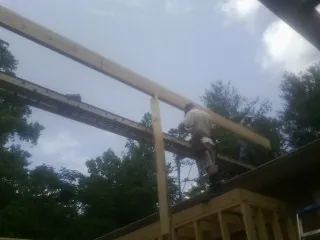 Carpenter setting a ridge beam over a new addition frame — Ice Dam Removal by Roofing Brothers in Buies Creek