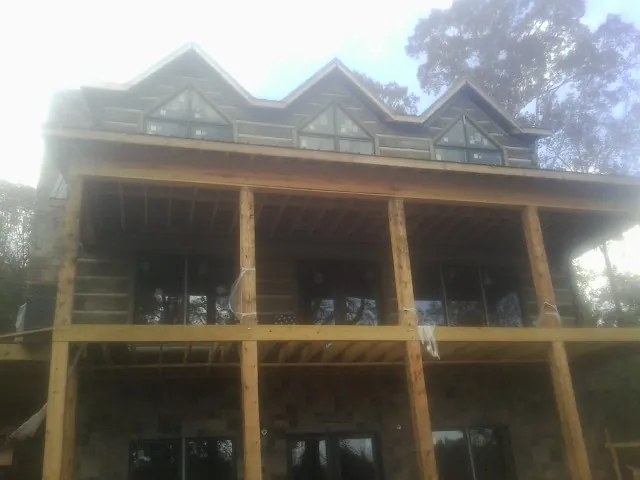 Dormers and porch framing on a large log home under construction — Roof Coating work by our crew in Buies Creek