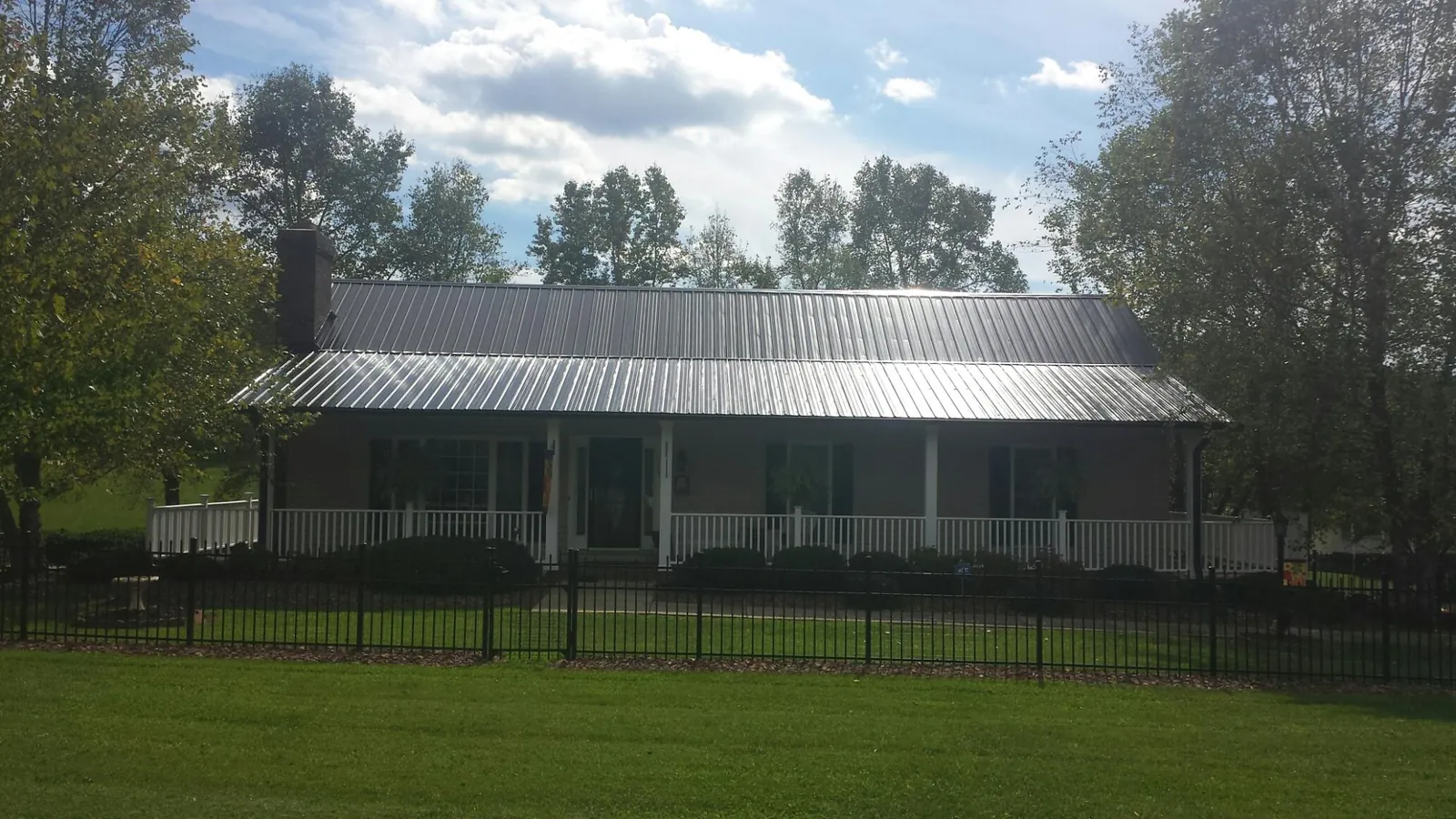 Gray metal roof on a brick ranch with a full width front porch — Gutter Guard Installation work by our crew in Buies Creek