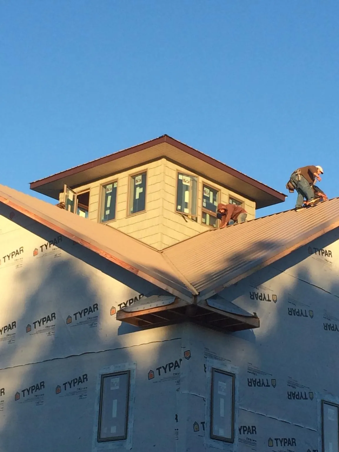 Roofers working around a rooftop cupola on a new metal roof at sunset — Roof Waterproofing in Buies Creek by Roofing Brothers